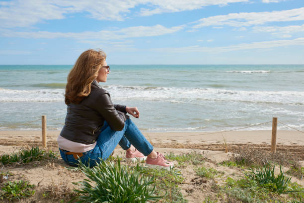 istock Woman sitting at the beach 994263754