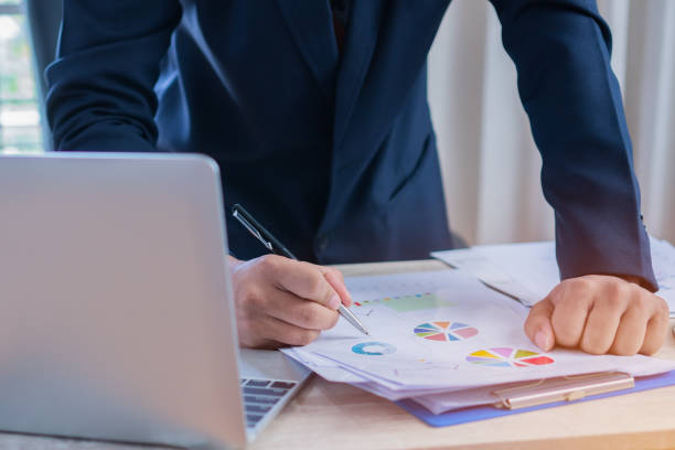 istock Document Report and business busy Concept: Businessman Manager checking and signing documents reports papers with calculator, laptop computer on stacks of paper files in modern office. 994269974
