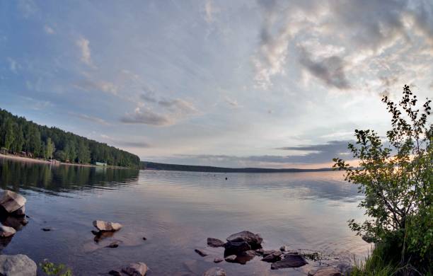 istock gray evening sky over the lake, orange sun, fish-eye 994270140