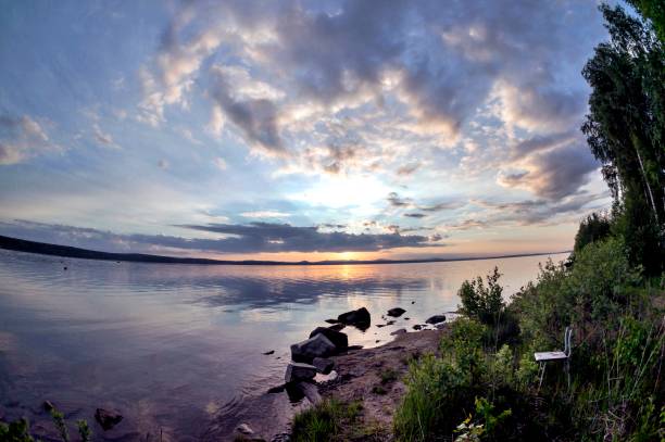 istock gray evening sky over the lake, orange sun, fish-eye 994270318