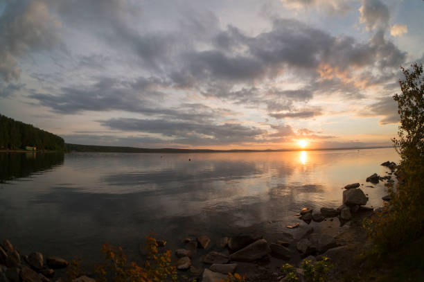 istock gray evening sky over the lake, orange sun, fish-eye 994272788