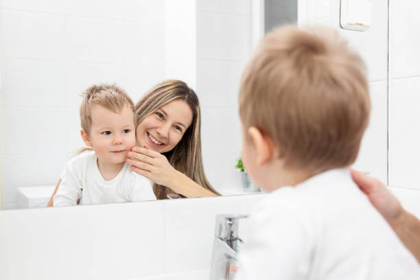 ママ彼女の息子彼の顔の洗い方を教える - toothbrush human teeth women healthy lifestyle ストックフォトと画像