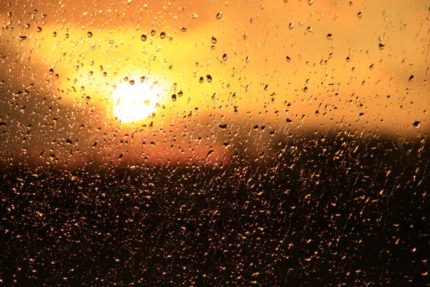 istock Rain outside window on sunset background. Water drops on glass during raining 994274000