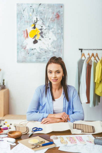 istock attractive seamstress sitting at working table and looking at camera 994274330