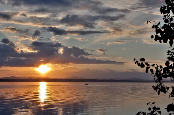istock gray evening sky over the lake, orange sun 994274400