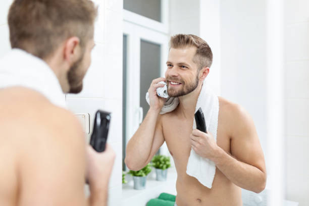 istock Handsome bearded man trimming his beard with a trimmer 994276622