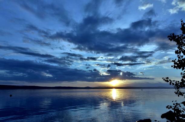 istock dark blue evening sky over the lake, orange sun 994276638