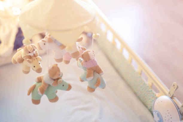 close-up baby crib with musical animal mobile at nursery room. hanged developing toy with plush fluffy animals. happy parenting and childhood, expectation delivery of a child concept - using mobile imagens e fotografias de stock