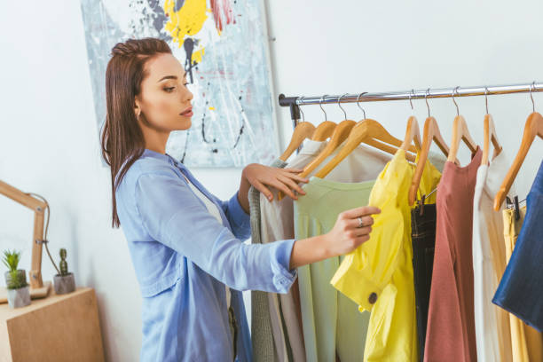istock beautiful designer looking at shirts on hangers 994277426