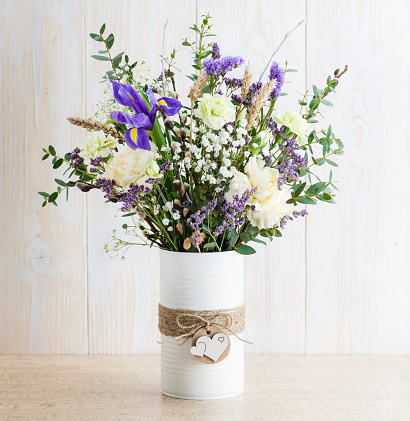 Fresh flowers in a vase on a wooden background in rustic style