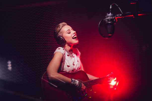 passionate singer playing the guitar and recording song in studio - singer imagens e fotografias de stock