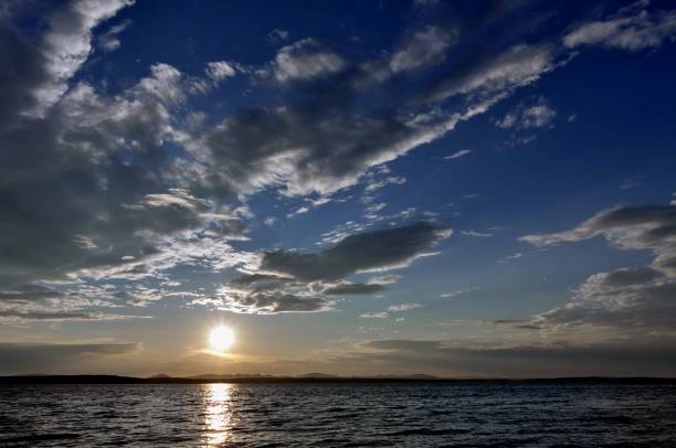 istock dark blue evening sky over the lake, orange sun 994280972