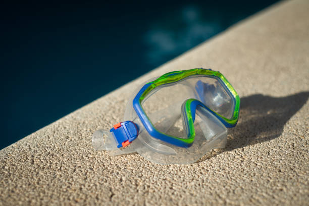 Snorkel Mask on Deck Beside Swimming Pool at a Holiday Villa Swim Mask Beside Pool in Summer vacation rental mask stock pictures, royalty-free photos & images