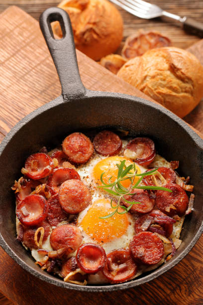 istock Cooked egg and sausages on frying pan 994281542
