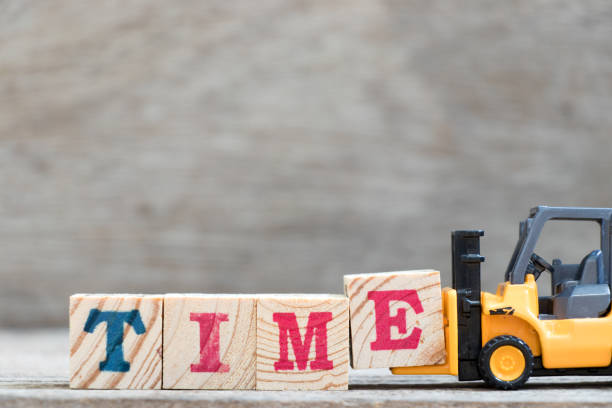 istock Toy forklift hold letter block E to complete word time on wood background 994281662