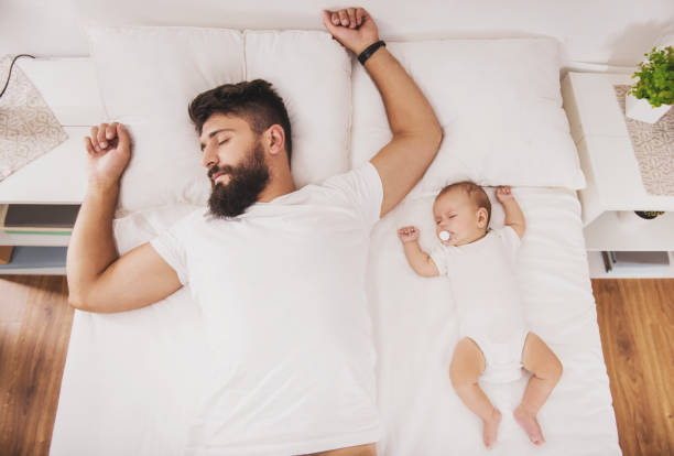Top view. Bearded Father Sleeps with Baby in Bed. Top view. Bearded Father Sleeps with Baby in Bed. Little Newborn Child in White Bed. Parenthood Concepts. Love and Happiness. Taking Care of New Life. Family, Love, Happiness Concepts. man sleeping top view stock pictures, royalty-free photos & images