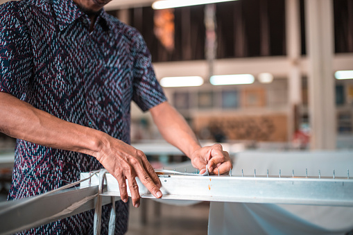 Shot of man setting up silk fabric for coloring in a batik workshop in Kuala Lumpur, Malaysia.