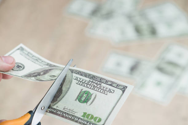istock Scissors cut dollars in the hands 994298188