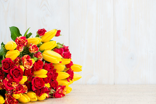 Bouquet of tulips and bush roses on a wooden background. Copyspace