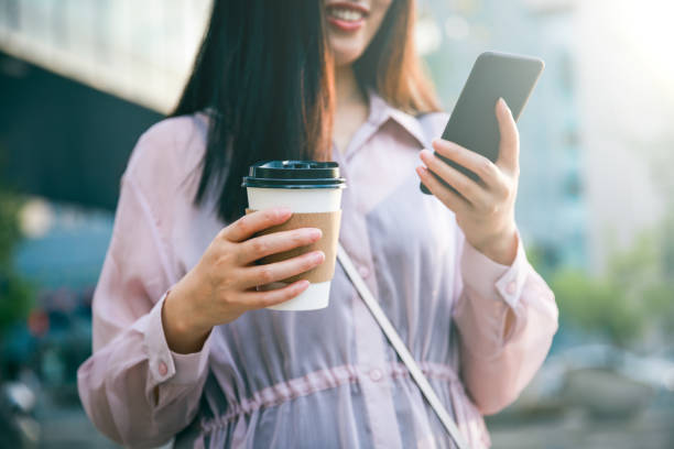 istock Young woman using phone and holding coffee 994308952