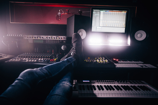 Sound engineer taking a break and relaxing with feet up in professional music recording studio