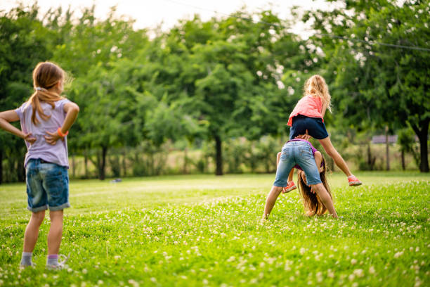 Back view three little girls playing in public park