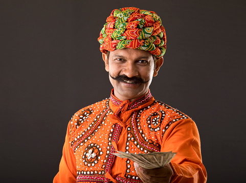 Indian man in traditional clothing holding paper currency