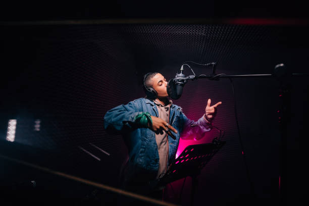 Young hipster African-American rapper recording songs in music recording studio Young fashionable hip hop singer singing and recording music in professional music recording studio sound recording equipment photos stock pictures, royalty-free photos & images