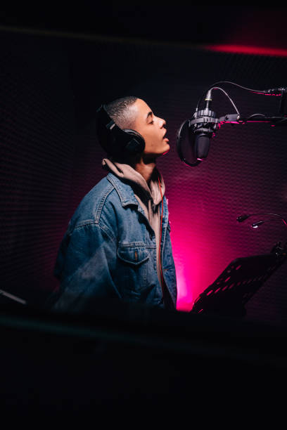 Young pop musician singing and recording song in music studio stock photo