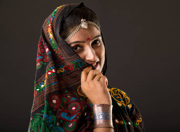 Beautiful Arabian woman portrait outdoors. Young Hindu woman. Portrait of beauty Indian model with bright make-up who hiding her face behind the veil standing over gold desert background.