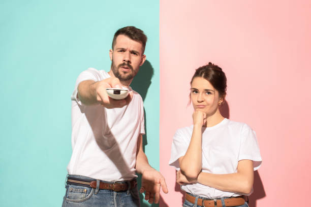 istock Couple bored watching tv with a the hand holding the remote control standing at studio 994339626