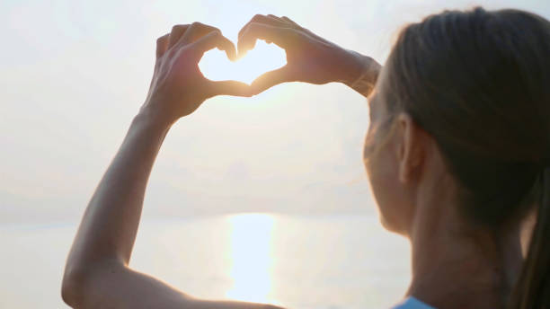 istock Female hands making heart shape gesture holding sun flare 994360934