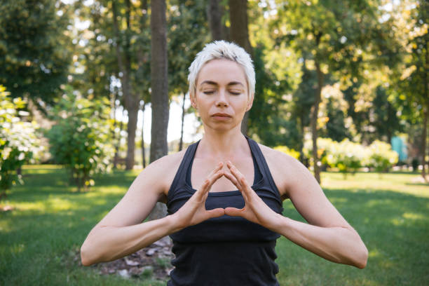 istock woman meditating with closed eyes in park 994363210