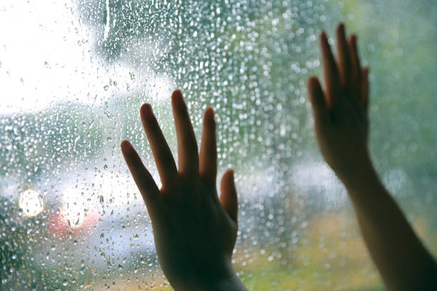 hand touching window on a rain day - water surface emotional stress shape nature imagens e fotografias de stock