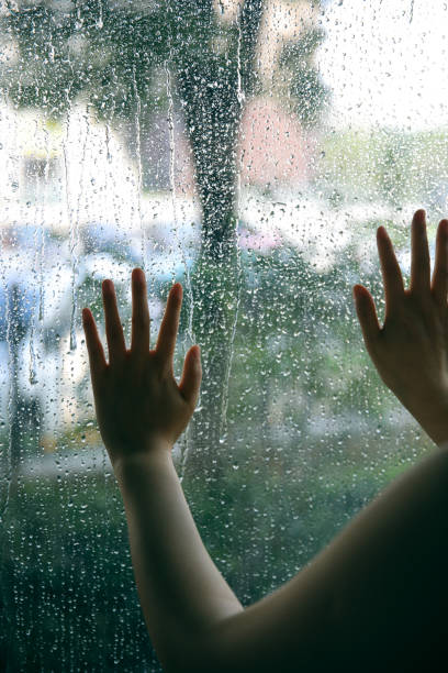 hand touching window on a rain day - water surface emotional stress shape nature imagens e fotografias de stock