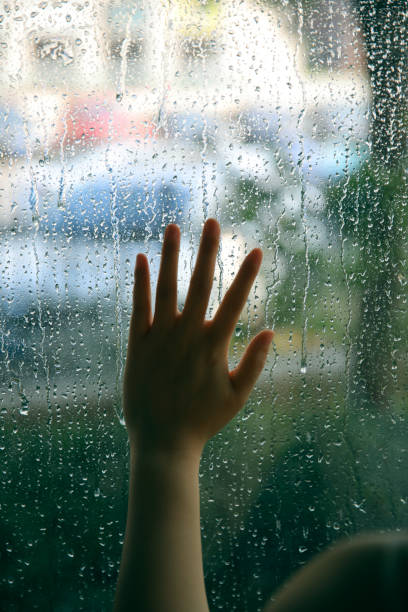 hand touching window on a rain day - water surface emotional stress shape nature imagens e fotografias de stock