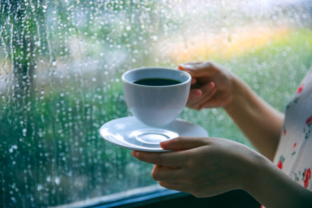 istock Woman drinking coffee by window on rainy day 994367202