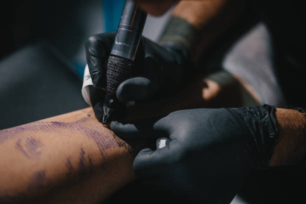 istock Tattoo artist working with tattoo machine on tattoo design 994390470