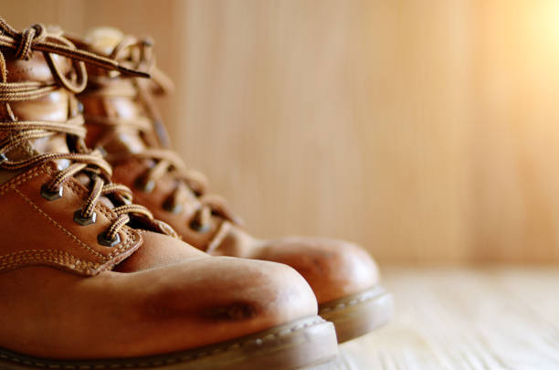 istock Yellow leather used work boots on wooden background closeup. Place for text 994403368