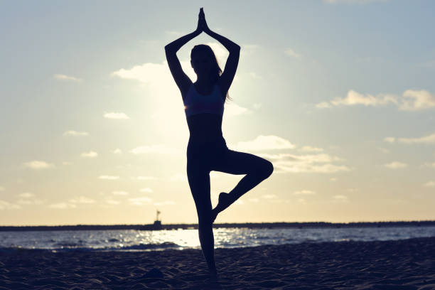 istock Silhouette young woman practicing yoga on the beach at sunset 994403830
