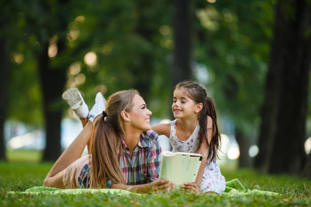 istock Mother and daughter reading book in a park 994415168