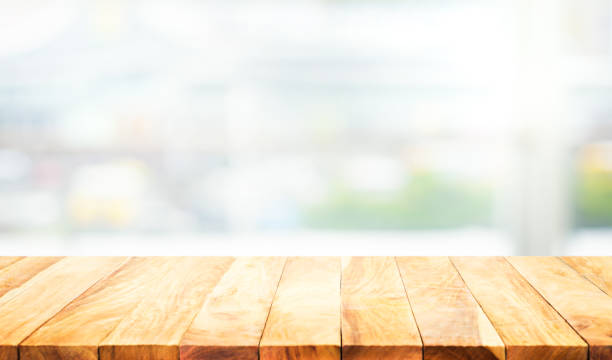 istock Wood table top on blur white glass wall background form office building 994415338