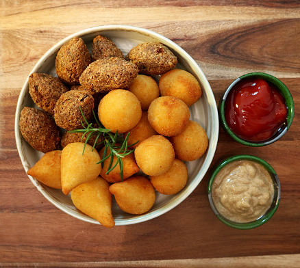 Traditional Brazilian snacks coxinha and quibe on wooden background. Top view.
