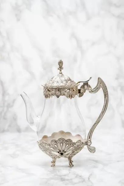 Decorative glass and metal jug on white marble