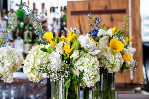Closeup of many wedding flower bouquet vase arrangement on table of reception dinner in restaurant, bar venue