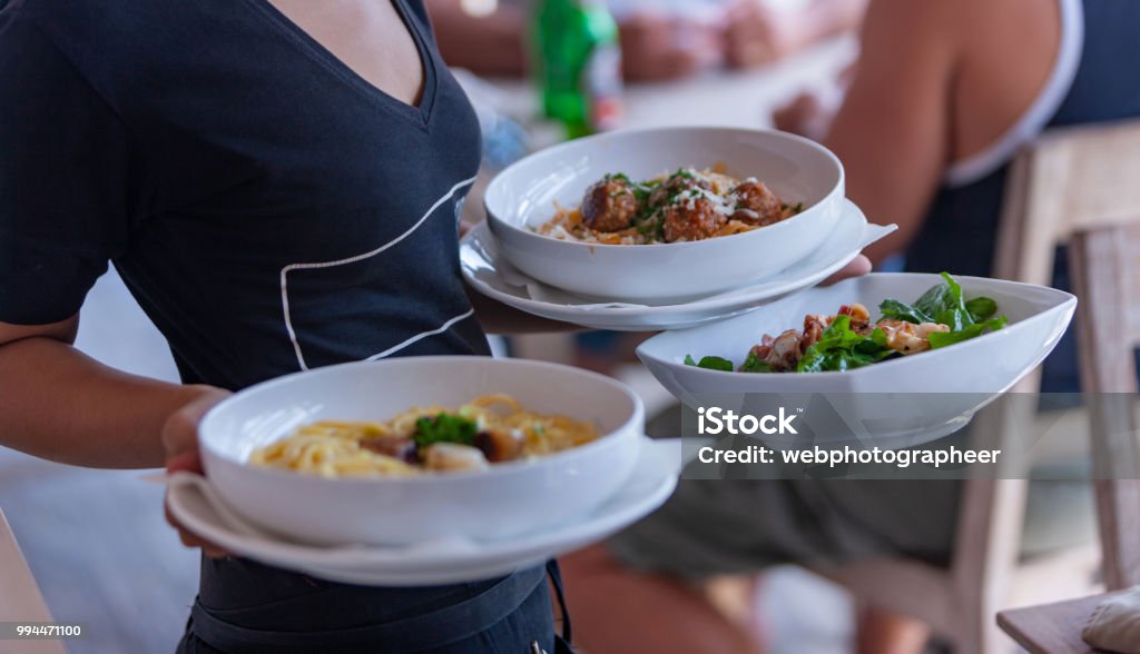 Waitress carrying plates Waitress carrying plates in outdoor cafe Waitress Stock Photo