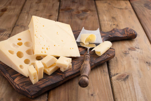 cheese with holes large and small. wooden board and knife. traditional dutch cheese. copy space. - cheese emmental cheese switzerland grated imagens e fotografias de stock