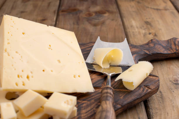 cheese with holes large and small. wooden board and knife. traditional dutch cheese. copy space. - cheese emmental cheese switzerland grated imagens e fotografias de stock