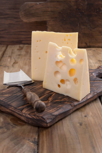 traditional dutch cheese with holes, on a vintage wooden board, wooden background and knife for cheese. dairy. copy space - cheese emmental cheese swiss culture cutting board imagens e fotografias de stock