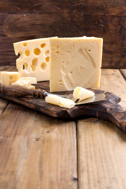 cheese with holes large and small. wooden board and knife. traditional dutch cheese. copy space. - cheese emmental cheese switzerland grated imagens e fotografias de stock